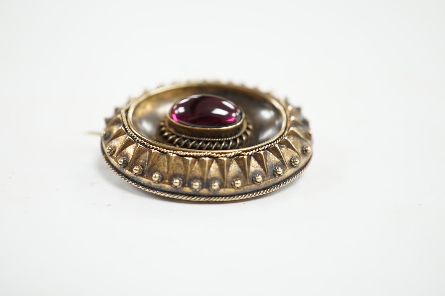 A Victorian yellow metal and single stone oval cabochon garnet set oval brooch, with glazed back, 33mm, gross weight 8.7 grams. Condition - fair